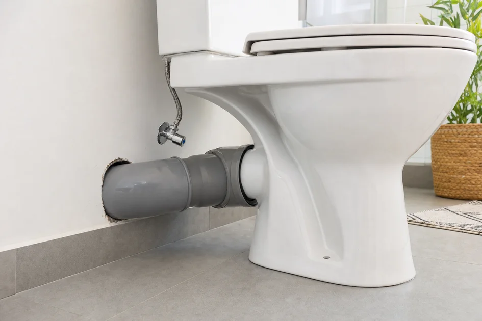 Évacuation WC en diamètre 100 mm avec raccord PVC visible sous la cuvette de toilette dans une salle de bain moderne